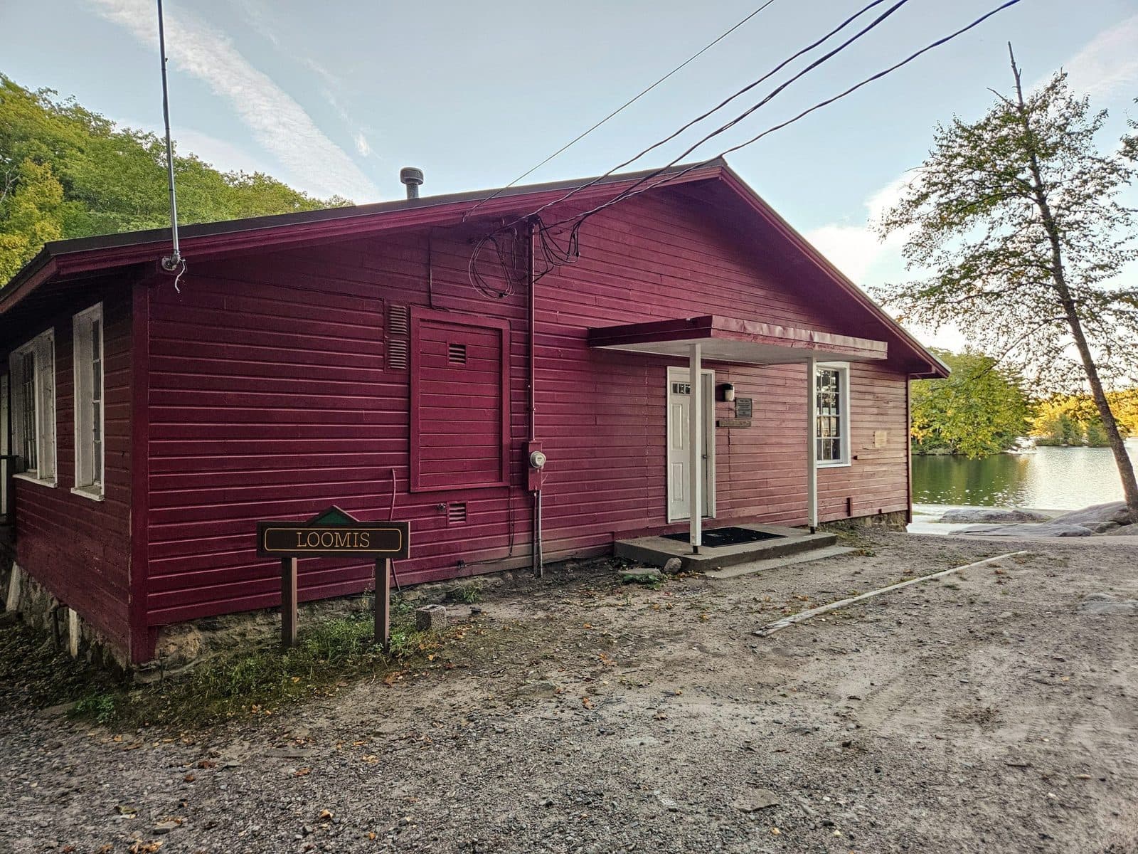 Loomis Hall, a long red cabin beside the lake at Camp Sequassen, with autumn trees behind it